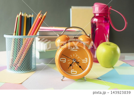 A workspace with school supplies and an alarm clock for studying. School supplies and study materials on a desk. "Back to school" concept. A workspace with school supplies and an alarm clock for studying. School supplies and study materials on a desk. "Back to school" concept. 143923839