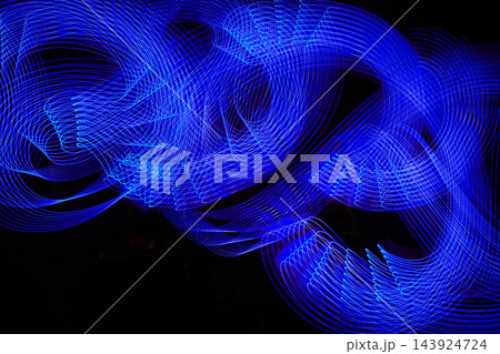 Blue neon light painting forming abstract waves in long exposure 143924724