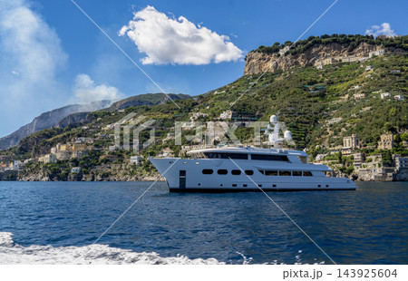 View of beautiful Amalfi town, Campania, Italy. Amalfi coast is most popular travel and holiday destination in Europe. Amalfi cityscape on coast line of mediterranean sea - big yacht 143925604