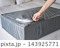 Hand closing zipper on gray fabric bedding storage bag filled with white duvet 143925771