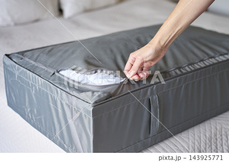 Hand closing zipper on gray fabric bedding storage bag filled with white duvet Hand closing zipper on gray fabric bedding storage bag filled with white duvet 143925771