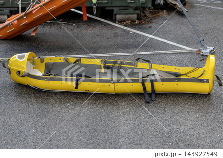 Yellow rescue stretcher lying on asphalt with securing straps 143927549
