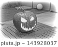 Carved pumpkin jack-o'-lantern with jagged teeth and triangular eyes on wooden table under soft ambient light, black and white closeup composition of spooky autumn decoration for Halloween party 143928037