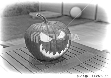 Carved pumpkin jack-o'-lantern with jagged teeth and triangular eyes on wooden table under soft ambient light, black and white closeup composition of spooky autumn decoration for Halloween party Carved pumpkin jack-o'-lantern with jagged teeth and triangular eyes on wooden table under soft ambient light, black and white closeup composition of spooky autumn decoration for Halloween party 143928037