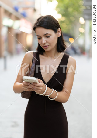 Slender female brunette with phone walks in vicinity of Passeig Nou in Barceloneta Slender female brunette with phone walks in vicinity of Passeig Nou in Barceloneta 143930294