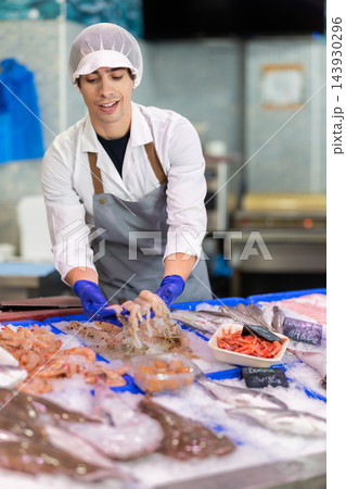 Young seller displaying seafood in fish store Young seller displaying seafood in fish store 143930296