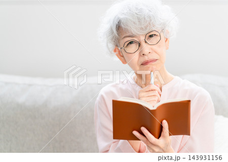 スケジュール帳を見るシニア女性 スケジュール帳を見るシニア女性 143931156
