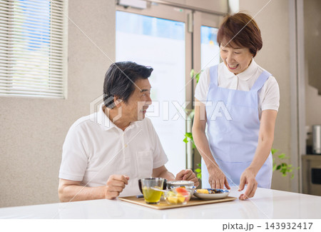 介護施設で食事を提供されるシニア男性とスタッフのシニアの女性 介護施設で食事を提供されるシニア男性とスタッフのシニアの女性 143932417