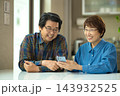 リビングで一緒にスマホを見るシニアの夫婦 143932525