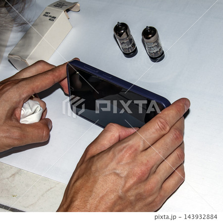 Nitra, Slovakia - August 4, 2026: Close View of Hands Using Smartphone Near Radio Tubes 143932884
