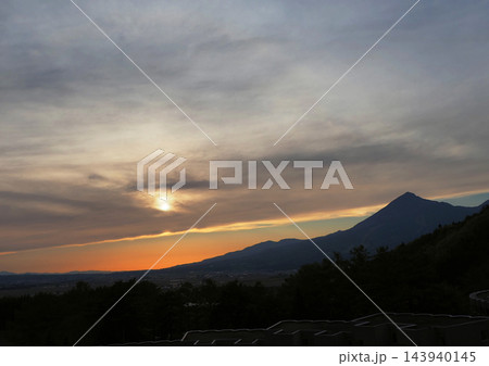 磐梯山の夕景。雲のカーテンに包まれる太陽と仕切られたオレンジ色と水色の空が印象的で綺麗だ。 143940145