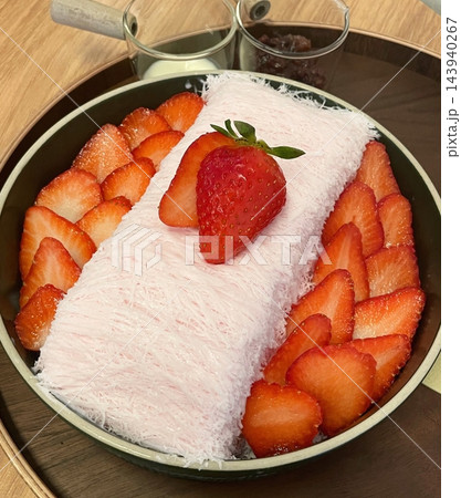 Soft and fluffy strawberry bingsu with finely shaved ice, sweet strawberry syrup, and fresh strawberry slices. A refreshing and delightful Korean dessert, perfect for a cool and fruity treat. 143940267
