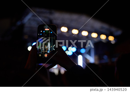 Person recording live concert on smartphone at night 143940520