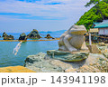 夏の晴れた日 二見浦で天の岩戸の前から伊勢湾の夫婦岩を背景に佇むカエルの石造を捉えた夏風景 143941198