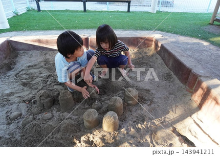 公園の砂場で仲良く一緒に砂の山を作って遊ぶ二人の男の子 143941211