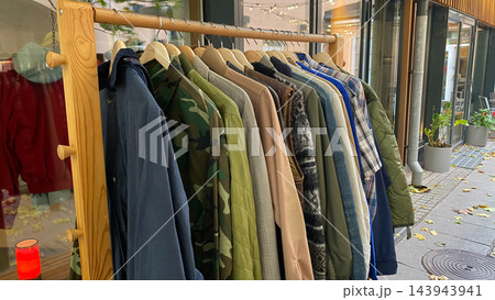 Assorted second hand jackets, coats and shirts hanging on wooden clothing rack at outdoor vintage clothing market Assorted second hand jackets, coats and shirts hanging on wooden clothing rack at outdoor vintage clothing market 143943941