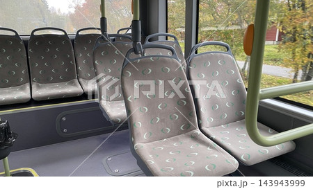 Empty modern city bus interior with gray patterned passenger seats and green handrails in public transportation vehicle Empty modern city bus interior with gray patterned passenger seats and green handrails in public transportation vehicle 143943999