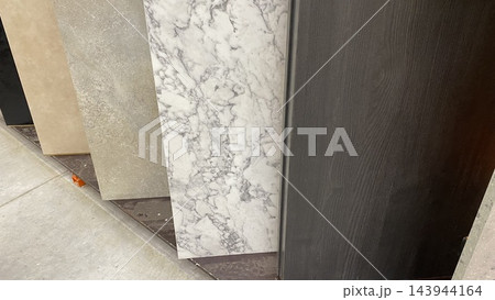 Large decorative wall panels with marble, stone and wood textures displayed vertically at home improvement store 143944164