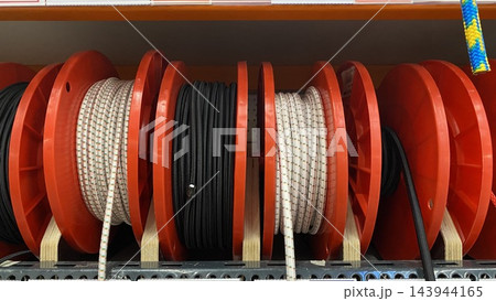 Assorted colorful ropes and cords wound on large reels displayed for sale at hardware store 143944165