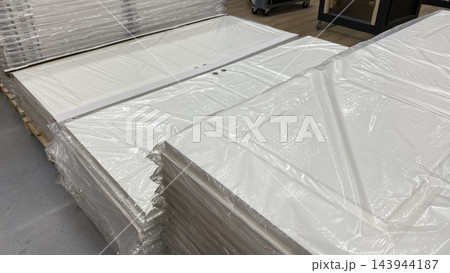 Stacks of white interior door panels wrapped in protective plastic film on wooden pallets at home improvement store Stacks of white interior door panels wrapped in protective plastic film on wooden pallets at home improvement store 143944187