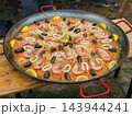 Giant Seafood Paella with Shrimp Mussels and Squid in Pan. Large seafood paella with shrimp, mussels, squid rings and lemon in large traditional pan. Spanish cuisine, outdoor food festival catering 143944241