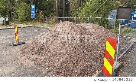 Pile of gravel at road construction site with safety barriers and warning markers Pile of gravel at road construction site with safety barriers and warning markers 143945019