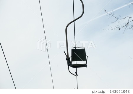 Ski lift chairs moving on cables against cloudy sky. 143951048