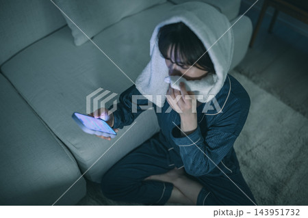 夜にタオルを頭に巻いてスマートフォンを見る女性 夜にタオルを頭に巻いてスマートフォンを見る女性 143951732