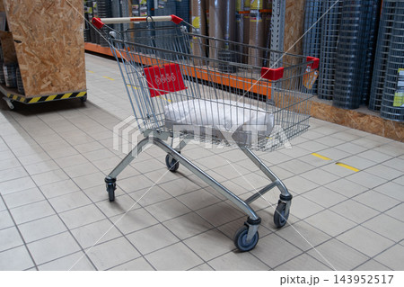 Shopping cart stands empty in a store aisle with building materials in the background 143952517