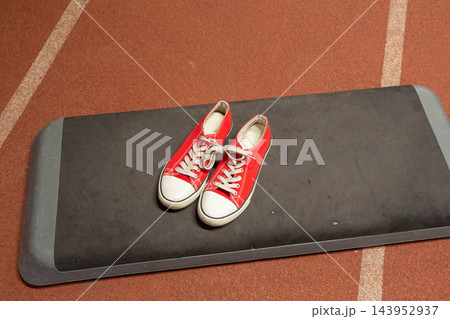 Red sneakers on gym mat in sports facility during training session Red sneakers on gym mat in sports facility during training session 143952937