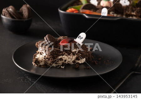Slice of Halloween Dirt Cake with gummy worm and RIP tombstone on black plate 143953145