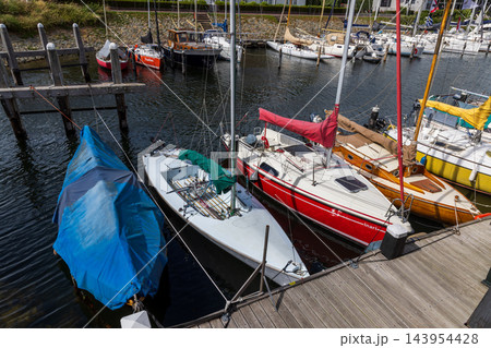 High angle horizontal perspective sailboat harbor marina wooden pier boardwalk moored yachts colorful hulls ropes clear water Veere Zeeland Netherlands European travel commercial 143954428
