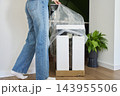 Woman removes protective plastic and foam packaging from new wine cooler 143955506