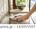 Hand wiping dust off a glass shelf with microfiber cloth 143955507