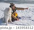 Young woman walking with fluffy samoyed dog in snowy winter park.  143958312