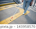A blind woman walks using a cane and tactile tiles. 143958570