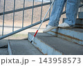 A blind woman descends a staircase. Close-up of her feet and a tactile stick. 143958573