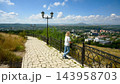 Female tourist standing at an observation point looking at a city view. Blonde woman on a paved walkway overlooking landscape, Pyatigorsk, Russia. Travel and sightseeing concept 143958703