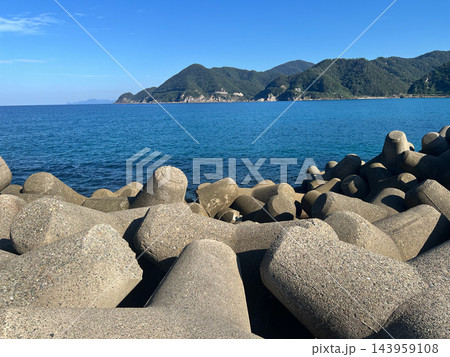 消波ブロックの向こうに広がる青い海と緑の山 晴天の海岸風景 横位置 写真素材 143959108