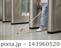 A blind woman passes through a turnstile in the subway. 143960520
