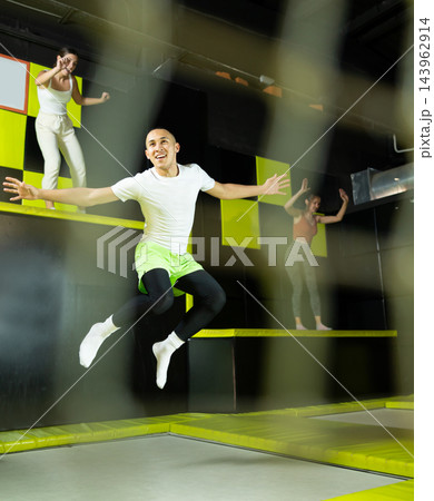 Fitness, fun, leisure and sport activity concept - happy man jumping on trampoline indoors Fitness, fun, leisure and sport activity concept - happy man jumping on trampoline indoors 143962914