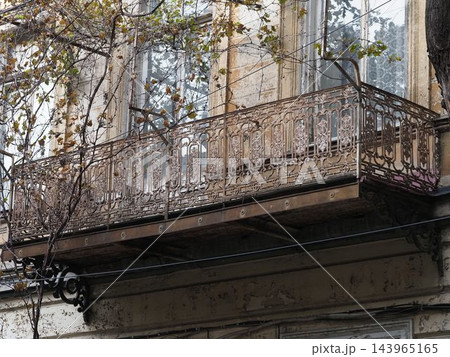 Vintage balcony with ornate black wrought iron railing on a light brick building facade. Vintage balcony with ornate black wrought iron railing on a light brick building facade. 143965165