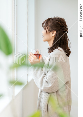紅茶を手に窓辺でひと息つく女性 紅茶を手に窓辺でひと息つく女性 143965497