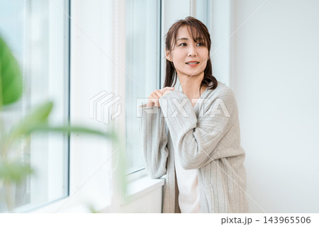 窓辺でくつろぐルームウェア姿の女性 143965506