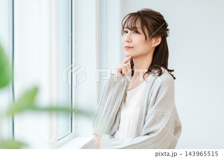 顎に指を添えて考える窓辺の女性 143965515