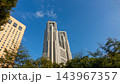 青空に映える東京都庁舎と新宿中央公園の木々・高層ビル群 143967357