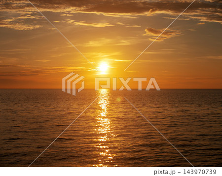 Golden sunset over the calm sea horizon with beautiful sun reflection on the water surface. 143970739