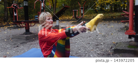 Mature woman practicing yoga and stretching outdoors in an autumn park. Active senior enjoying healthy aging, fitness, and vitality through outdoor workout and mindfulness. Mature woman practicing yoga and stretching outdoors in an autumn park. Active senior enjoying healthy aging, fitness, and vitality through outdoor workout and mindfulness. 143972205