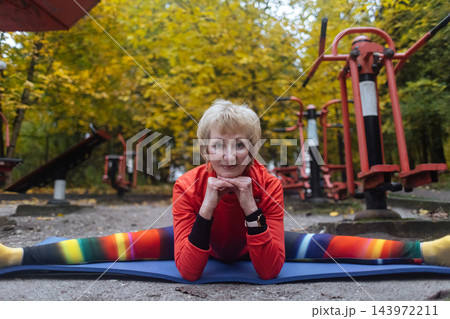 Mature woman practicing yoga and stretching outdoors in an autumn park. Active senior enjoying healthy aging, fitness, and vitality through outdoor workout and mindfulness. Mature woman practicing yoga and stretching outdoors in an autumn park. Active senior enjoying healthy aging, fitness, and vitality through outdoor workout and mindfulness. 143972211