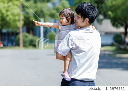 公園で小さな娘を抱っこする父親の後ろ姿 143976381